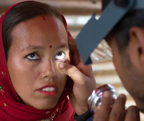 A health worker checks a woman's eyes for signs of trachoma.