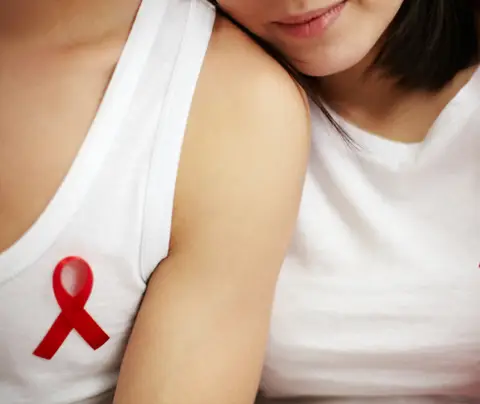 Two women wearing HIV awareness ribbons