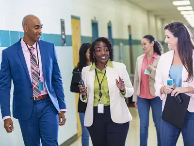 Group of male and female educators walking in school hallway