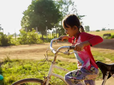 Photo of a young girl outside riding her bike