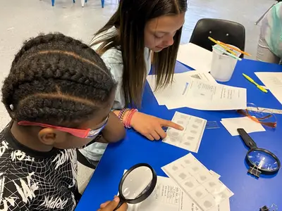 Two students study papers to solve a mystery
