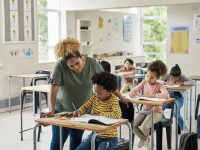 female teacher assisting male student at desk