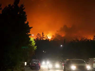 cars on a road with forest fires in the distance.