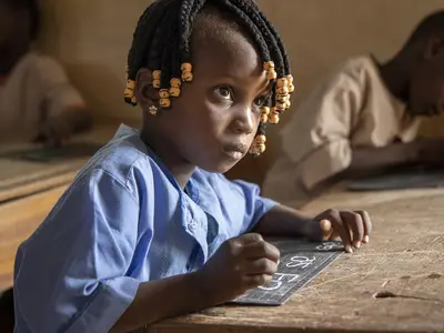 Girl with hand-held chalk board and piece of chalk in her hand