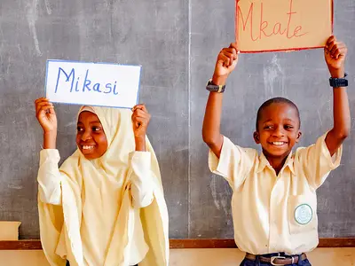 Tanzanian children hold up flash cards during a reading lesson.