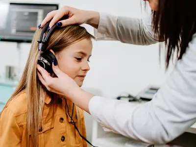 A middle-school girl gets a hearing test from an audiologist.