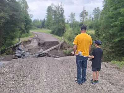 Man and boy standing in front of a washed away road