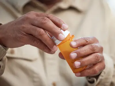 Older man opening prescription drug bottle