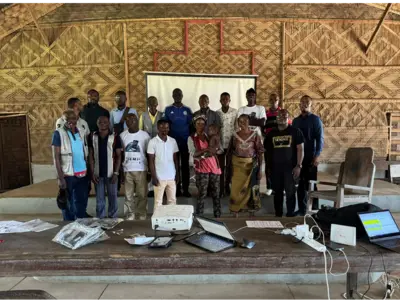 People gathering together for a picture. Majority men with a few women and a baby