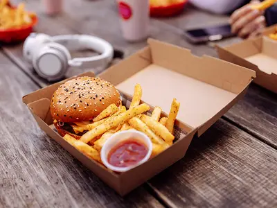 Cheeseburger, french fries, and ketchup in a cardboard to-go box