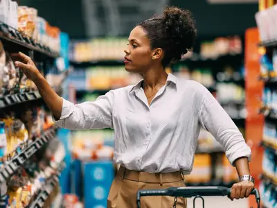 A woman selects food in a grocery store.