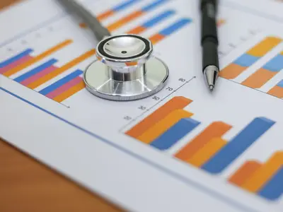 Stethoscope and pen resting on paper with charts