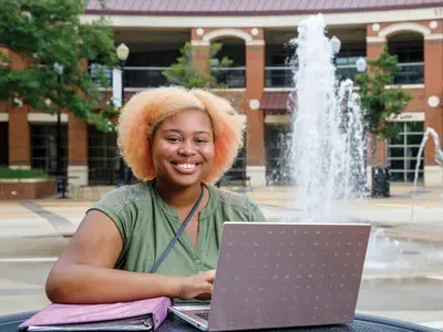 Young woman with laptop and binder