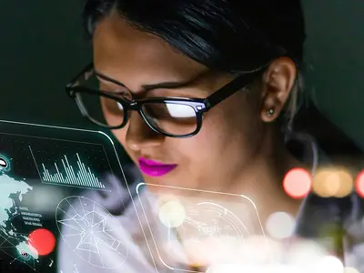 A person wearing glasses interacts with digital holograms in a tech-themed environment.