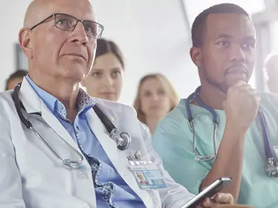 Doctors attentively listening during a lecture in a hospital conference room.