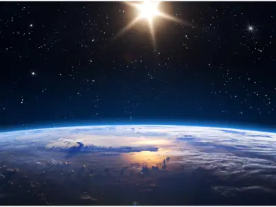 Earth with clouds and ocean reflecting sunlight in space, under a star-studded sky and bright sun.