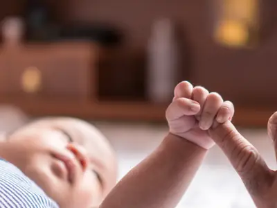 A closeup photo of a baby holding an adult's pinky