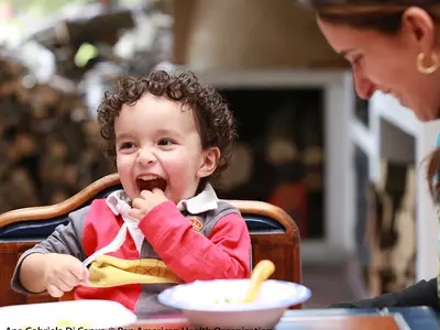 A mother and toddler eat at a table.