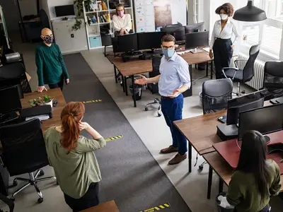 Workers use masks and social distancing while sharing office space during a pandemic.