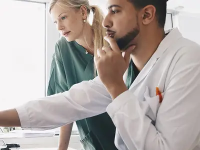 Doctor and Nurse look at a computer screen containing health data.