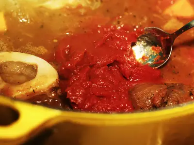 A closeup of a spoon in a simmering pot of beef stew.