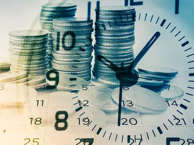 An illustration of a clock face superimposed over stacks of coins.