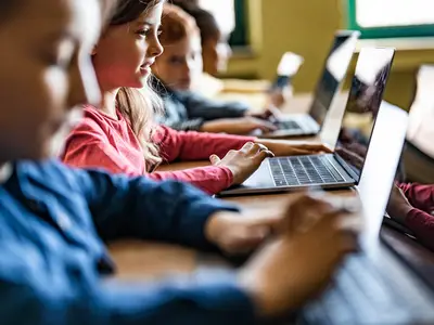 Children play educational games on laptop computers in a technology classroom. 