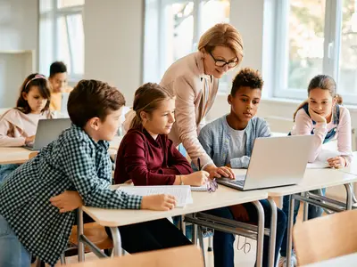 Group of elementary students having computer class with their teacher in the classroom