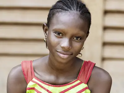 A teenage girl from Africa smiles at the camera.
