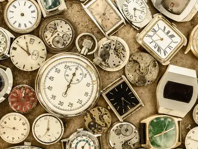A collection of antique clocks, watches, stopwatches, and clock parts.