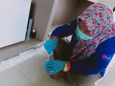 A technician in personal protective gear tests a sample.