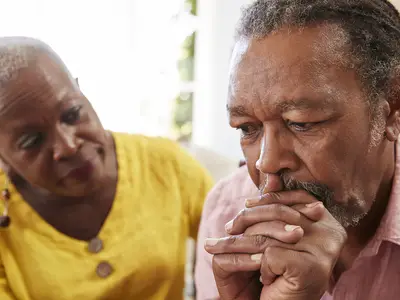 A senior Black couple with serious facial expressions.