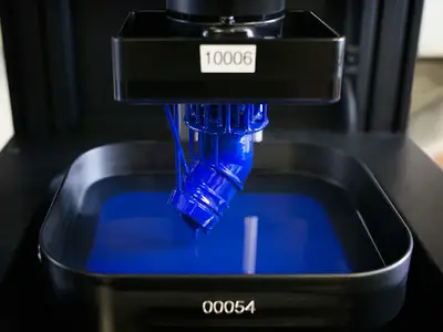 A state-of-the-art 3D printer creates an object from blue plastic