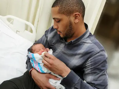 A father holds a newborn baby in a hospital room