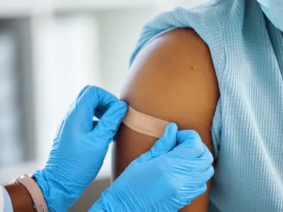 Health care worker applies band-aid post-vaccination