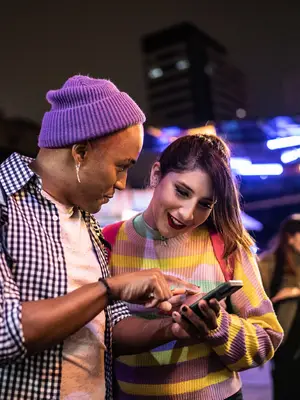 Photo of two young adults looking at a phone together