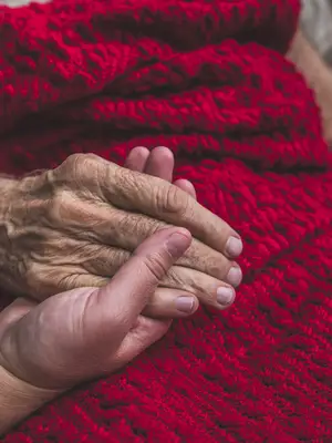 Photo of a caregiver holding an elderly patient's hand.