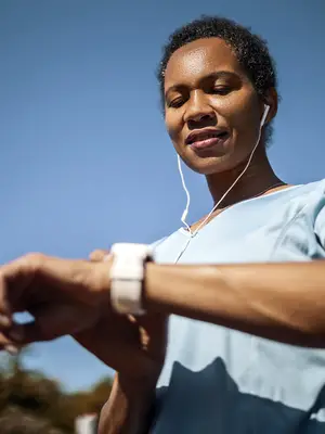 Photo of a runner checking a smartwatch and wearing ear buds.