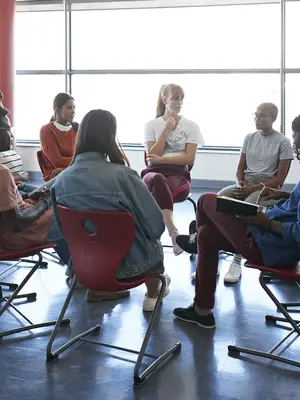 Photo of a group of young adults having a discussion in a circle.