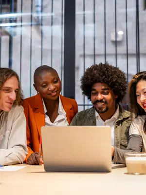 Photo of four colleagues gathered around a laptop.