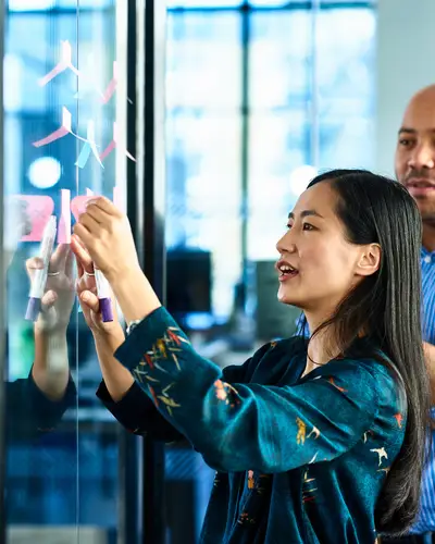 Coworkers brainstorming with sticky notes on a window