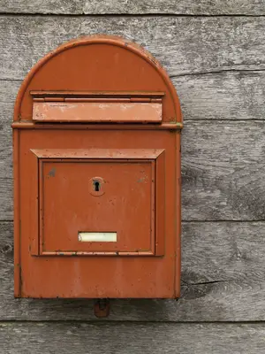 Photo of a red mailbox on a wooden wall.