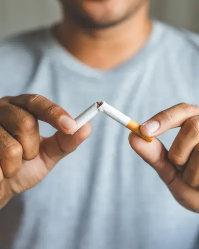 A closeup of a man breaking a cigarette in half.