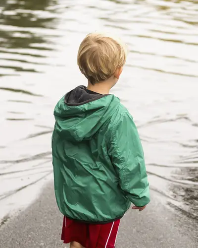 Little boy looking at big puddle of water