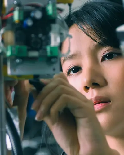A female robotics student works on a motor.