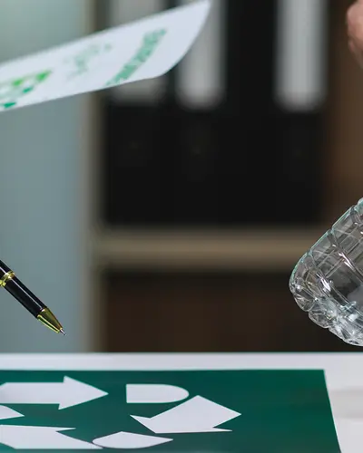 A closeup of two people holding plastic bottles and pens while looking at a calendar