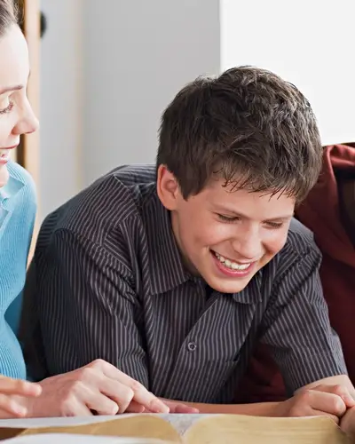 A group of middle school students laughing and reading at a table