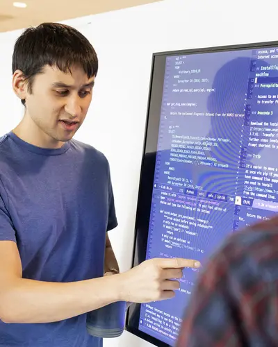 Data scientists from RTI gather around a large screen to look at a project.