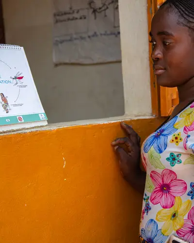 Woman looks at an educational malaria sign