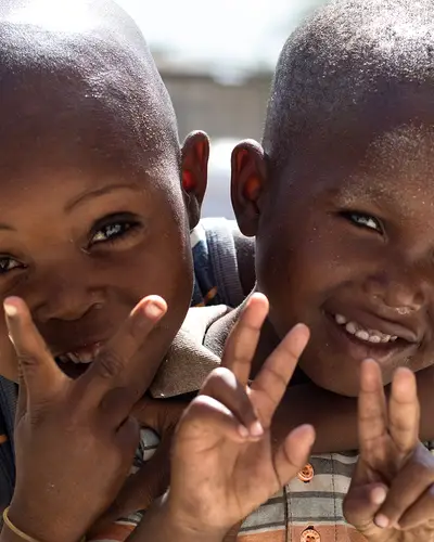 Two Haitian children hug and smile in a courtyard.